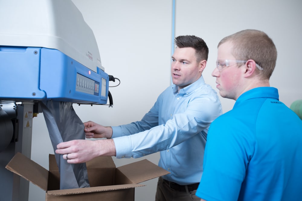Man teaching employee how to use bagging machine