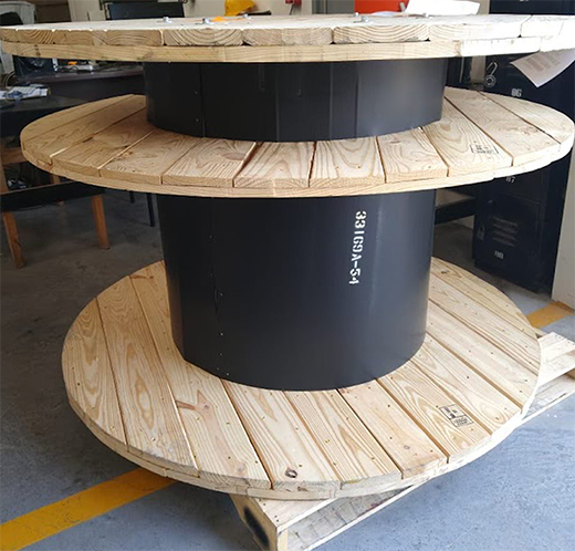 Large wooden cable spool in manufacturing facility.
