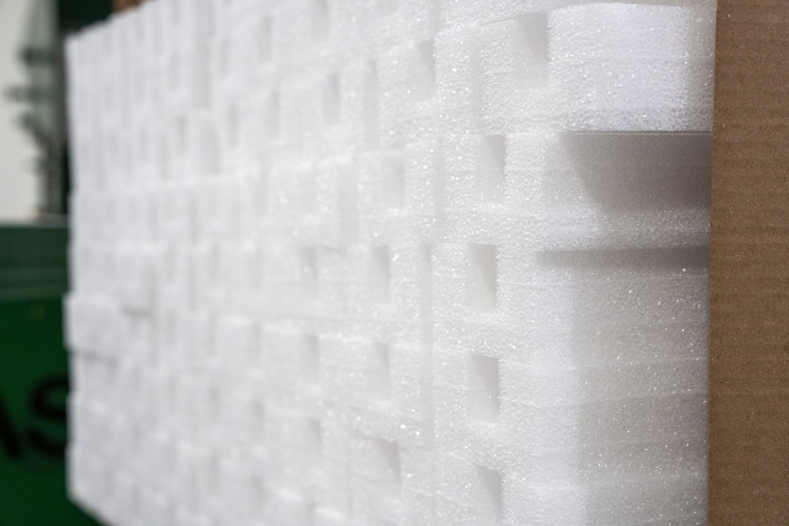 Stacked white foam sheets for packaging protection.