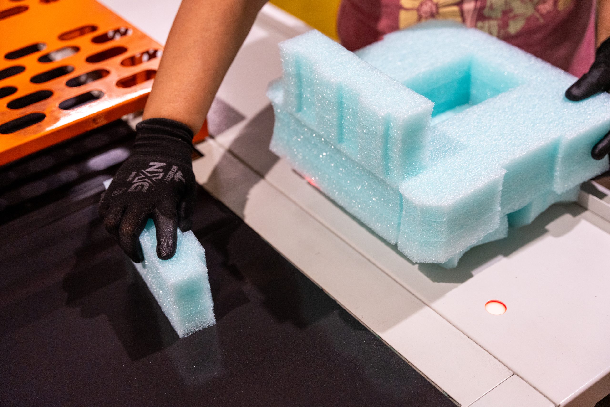 Person handling foam pieces at workshop table.